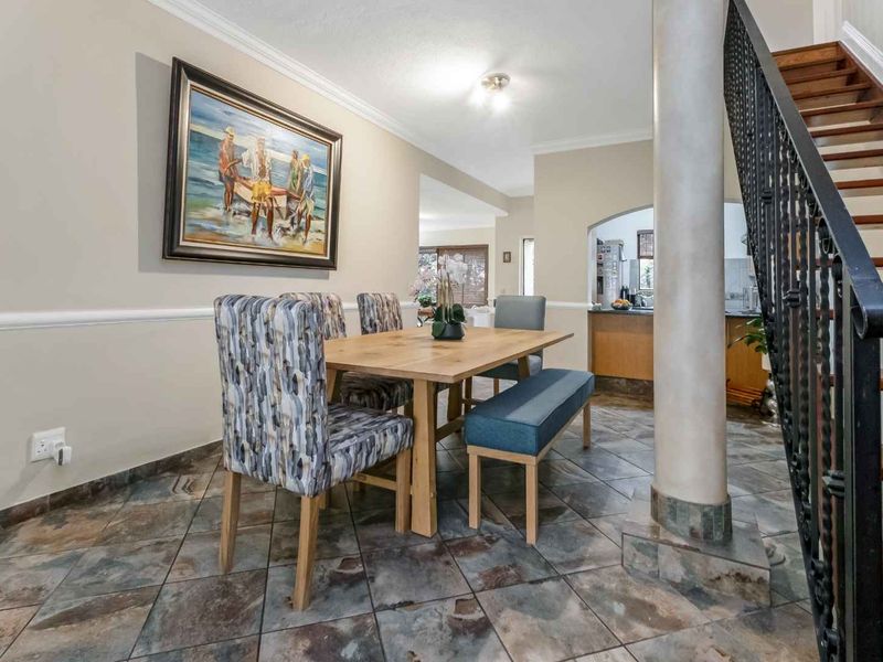 Dining area featuring tiled flooring, decorative chair rail molding, and an open-plan layout with a staircase and wrought iron railing.
