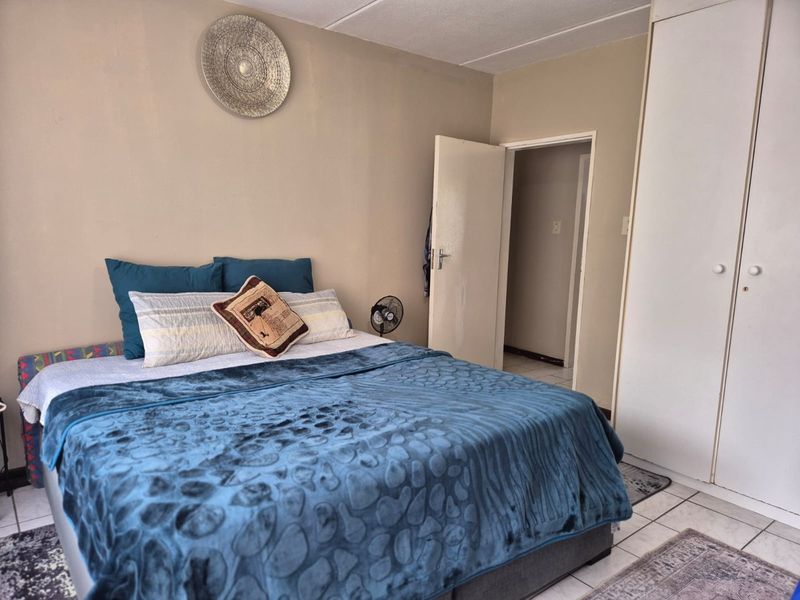 A bedroom featuring tiled flooring and built-in cupboards, providing functional storage space.