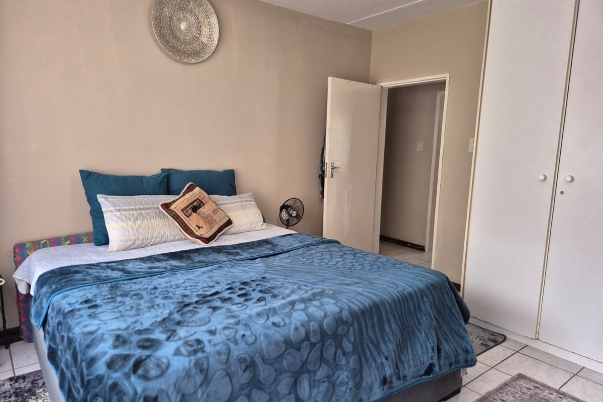 A bedroom featuring tiled flooring and built-in cupboards, providing functional storage space.
