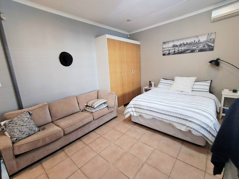 A bedroom featuring tiled flooring, a built-in wardrobe, and a wall-mounted split-system air conditioner.
