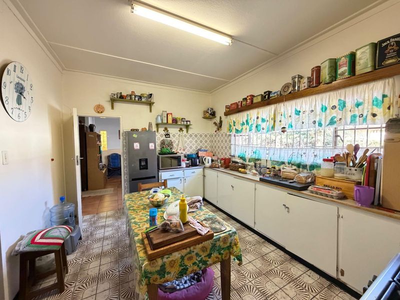 A functional kitchen featuring original cabinetry, tiled backsplash, and tiled flooring, offering potential for modernization and layout optimization.