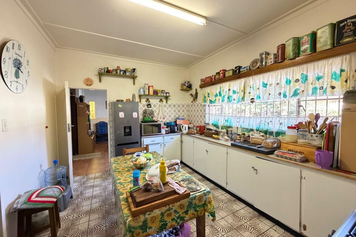 A functional kitchen featuring original cabinetry, tiled backsplash, and tiled flooring, offering potential for modernization and layout optimization.