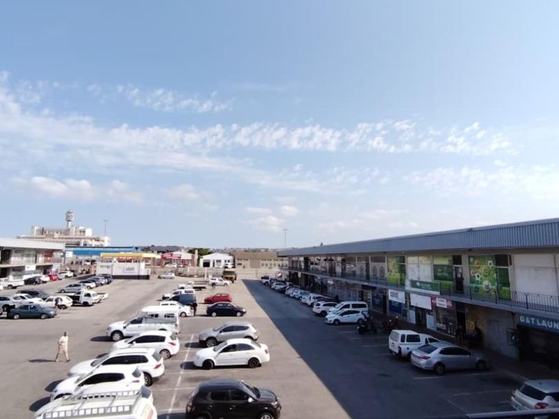 Elevated view overlooking a commercial parking lot and surrounding mixed-use retail buildings on a clear day.