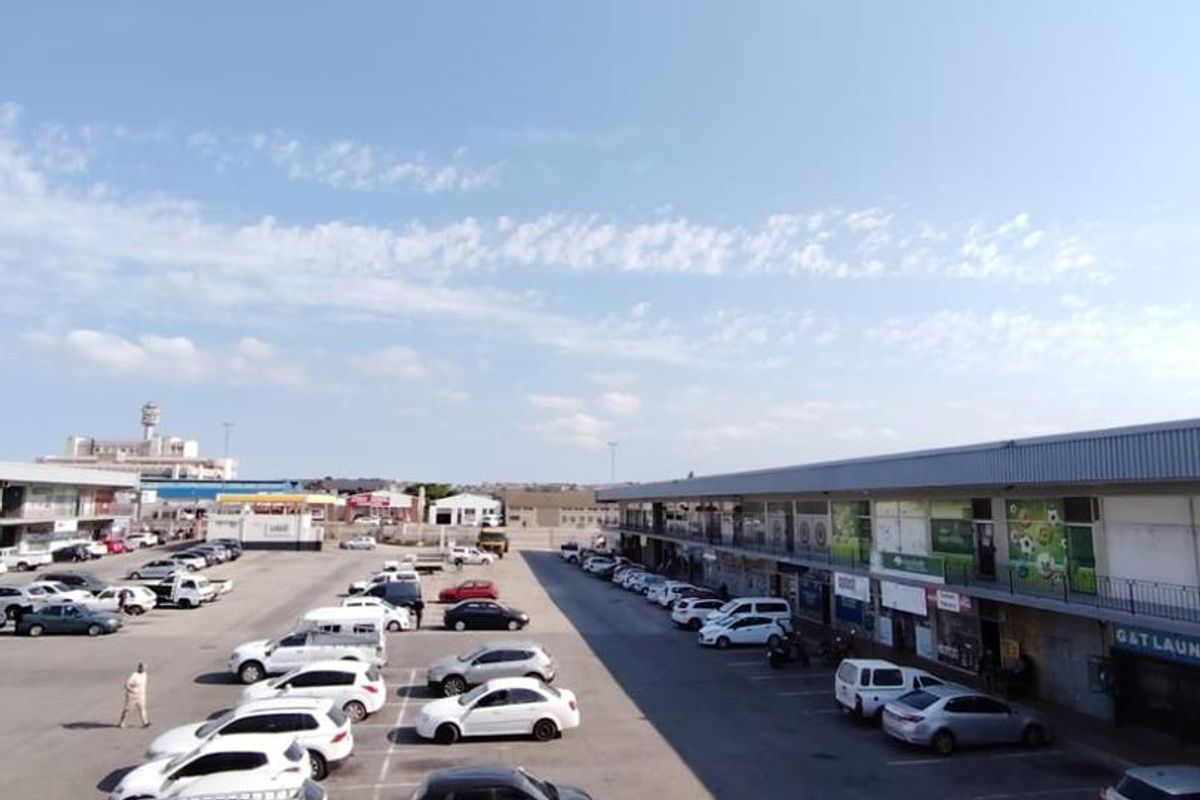 Elevated view overlooking a commercial parking lot and surrounding mixed-use retail buildings on a clear day.