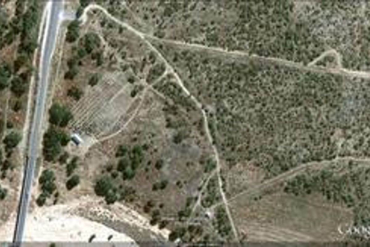 An aerial view of a large, undeveloped commercial land parcel featuring natural vegetation and existing dirt access tracks.