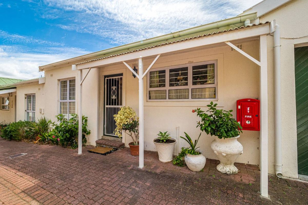Front entrance of the townhouse featuring a covered patio area, paved driveway, and installed fire safety equipment.