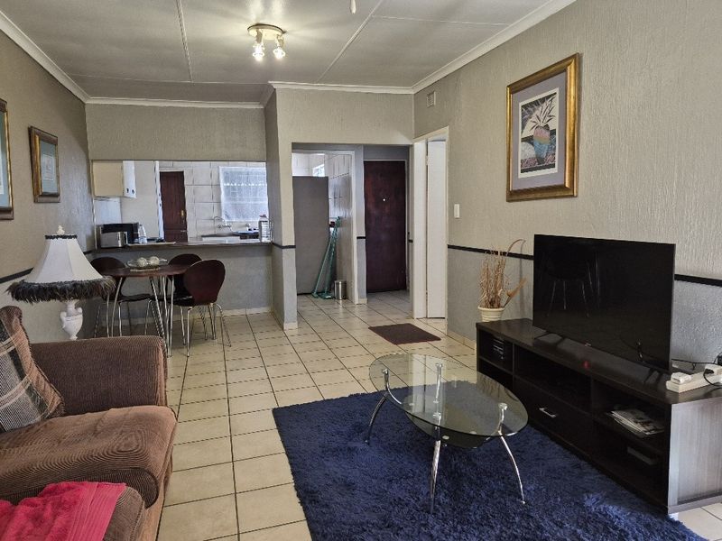 Open plan living and dining area featuring tiled flooring and a kitchen pass-through, offering a functional layout with potential for modern updates.