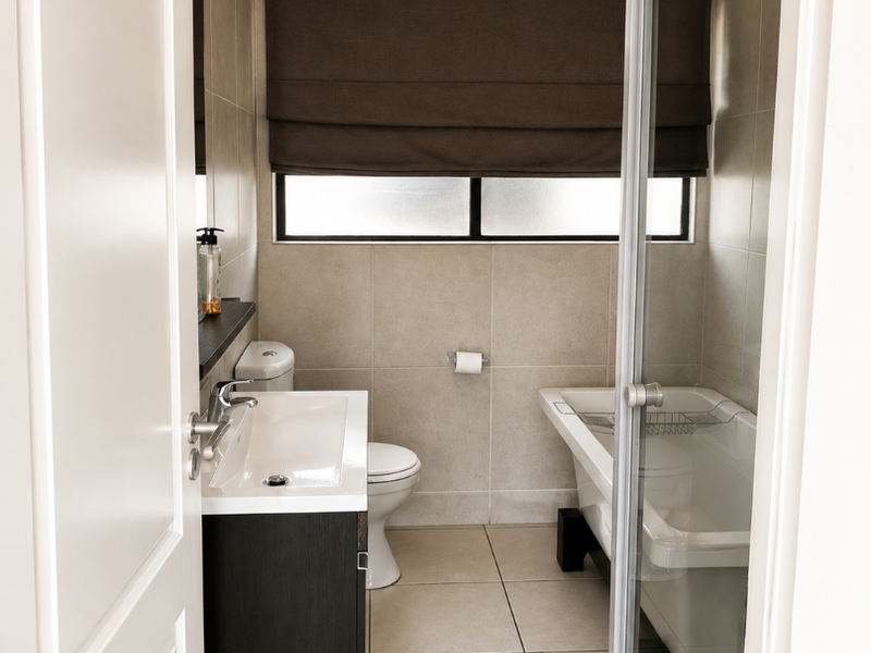 A modern bathroom featuring a wall-mounted vanity, a separate shower enclosure, and a bathtub, finished with neutral floor-to-ceiling tiles.