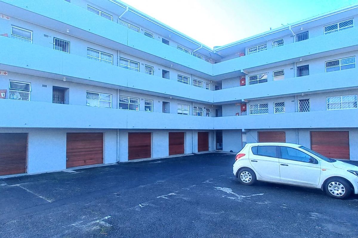 Exterior view of a multi-story apartment complex featuring ground-level garages and open-air walkways on upper levels.