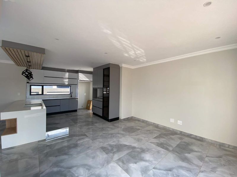 Modern open-plan kitchen area featuring sleek grey cabinetry, a central island, and polished large-format floor tiles in a contemporary home.