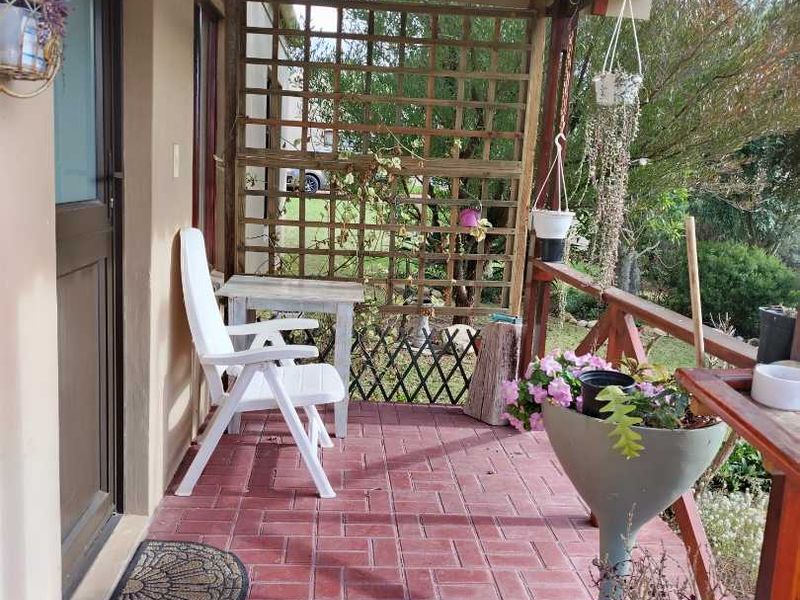 A covered patio area featuring brick paving, a timber pergola structure, and a wooden lattice privacy screen overlooking the garden.