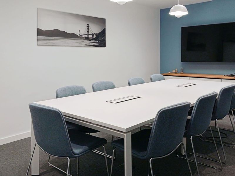 A modern, well-maintained office meeting room featuring a large conference table, built-in storage cabinetry, and professional pendant lighting.