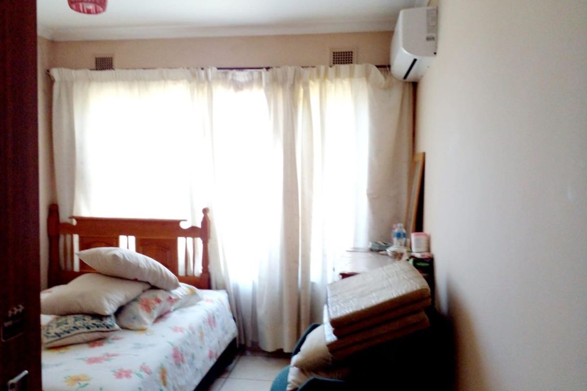 A bedroom featuring tiled flooring, an installed air conditioning unit, and large windows with curtains.