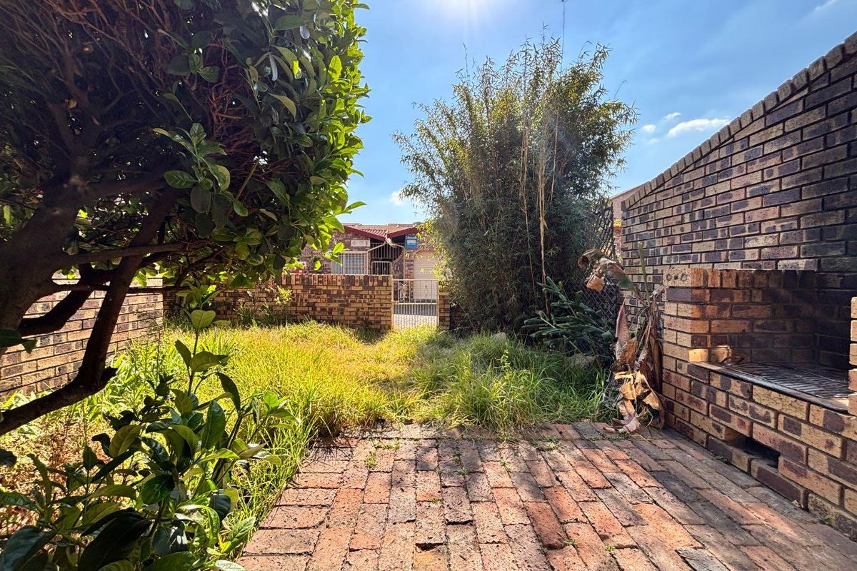 Rear garden area featuring a brick paved patio, built-in brick braai, and enclosed brick boundary walls.