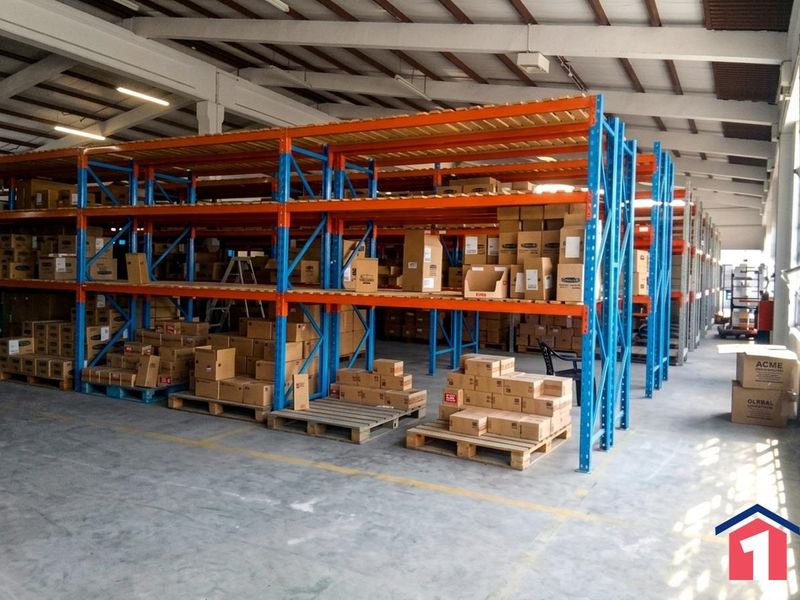 Spacious industrial warehouse featuring high-clearance steel racking systems, durable concrete flooring, and exposed roof trusses, ideal for storage and logistics operations.