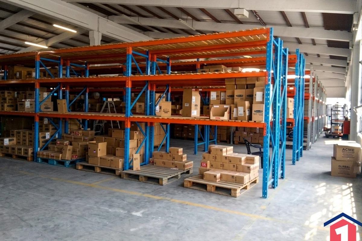Spacious industrial warehouse featuring high-clearance steel racking systems, durable concrete flooring, and exposed roof trusses, ideal for storage and logistics operations.