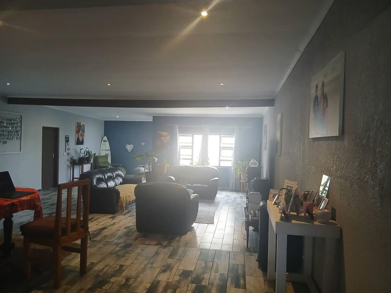 Spacious living area featuring tiled flooring, recessed downlighting, and an exposed ceiling beam, offering a versatile layout for comfortable family living.