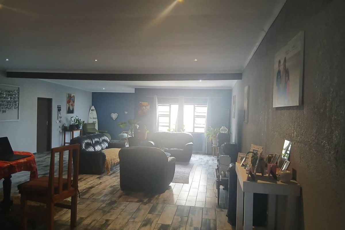 Spacious living area featuring tiled flooring, recessed downlighting, and an exposed ceiling beam, offering a versatile layout for comfortable family living.