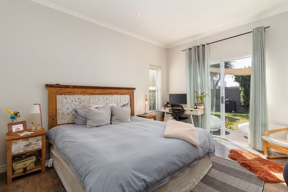 Spacious bedroom featuring laminate flooring, recessed lighting, and a sliding glass door providing direct access to the outdoor patio and garden area.
