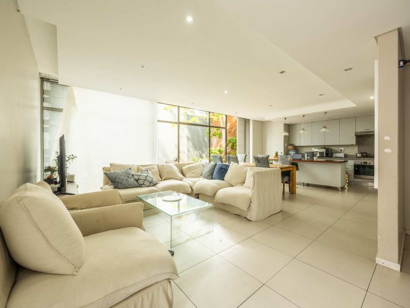 Spacious open-plan living and kitchen area featuring tiled floors, recessed lighting, and large windows that provide ample natural light.