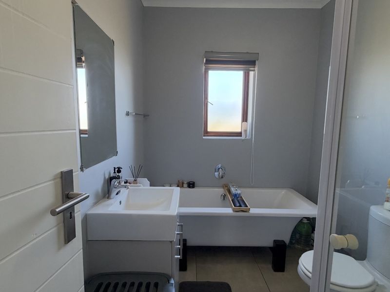 A functional bathroom featuring a vanity with basin, a bathtub, and a toilet, finished with neutral wall tones and tiled flooring.
