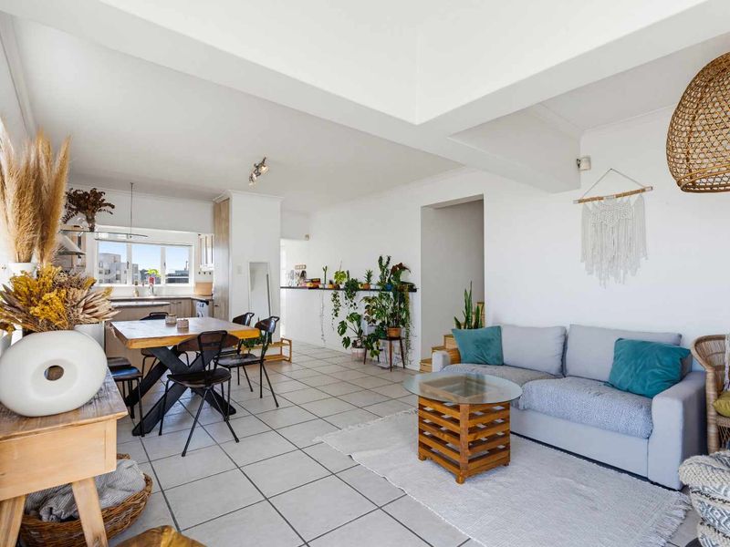 Spacious open-plan living and dining area featuring tiled flooring, a recessed ceiling, and an integrated kitchen with functional cabinetry.