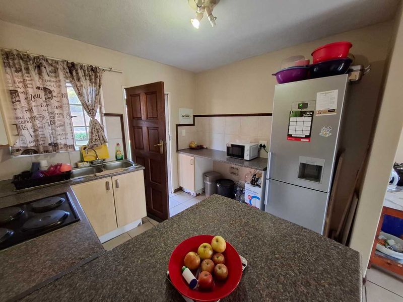 A functional kitchen featuring laminate cabinetry, durable countertops, a double bowl sink, and a built-in hob with tiled backsplash.