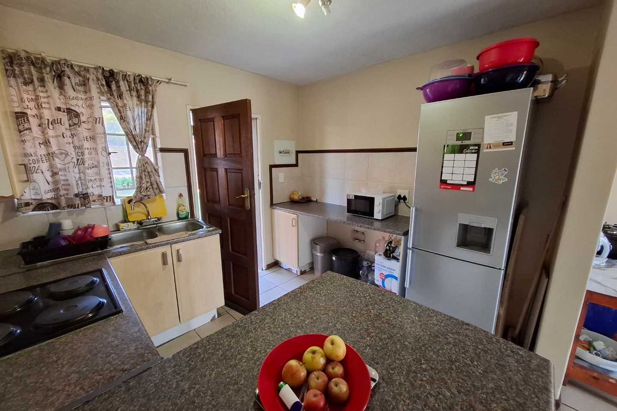 A functional kitchen featuring laminate cabinetry, durable countertops, a double bowl sink, and a built-in hob with tiled backsplash.
