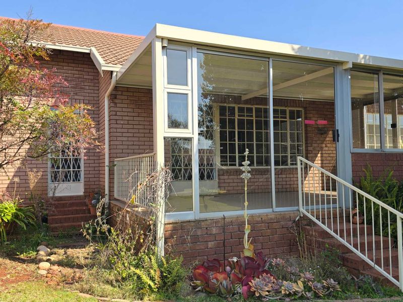 An enclosed patio area featuring sliding glass doors, brick exterior walls, and metal railings, providing a transition space between the home and garden.
