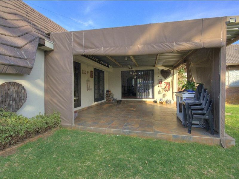 A covered outdoor patio area featuring tiled flooring, canvas drop-down blinds, and direct access to the home through sliding glass doors.