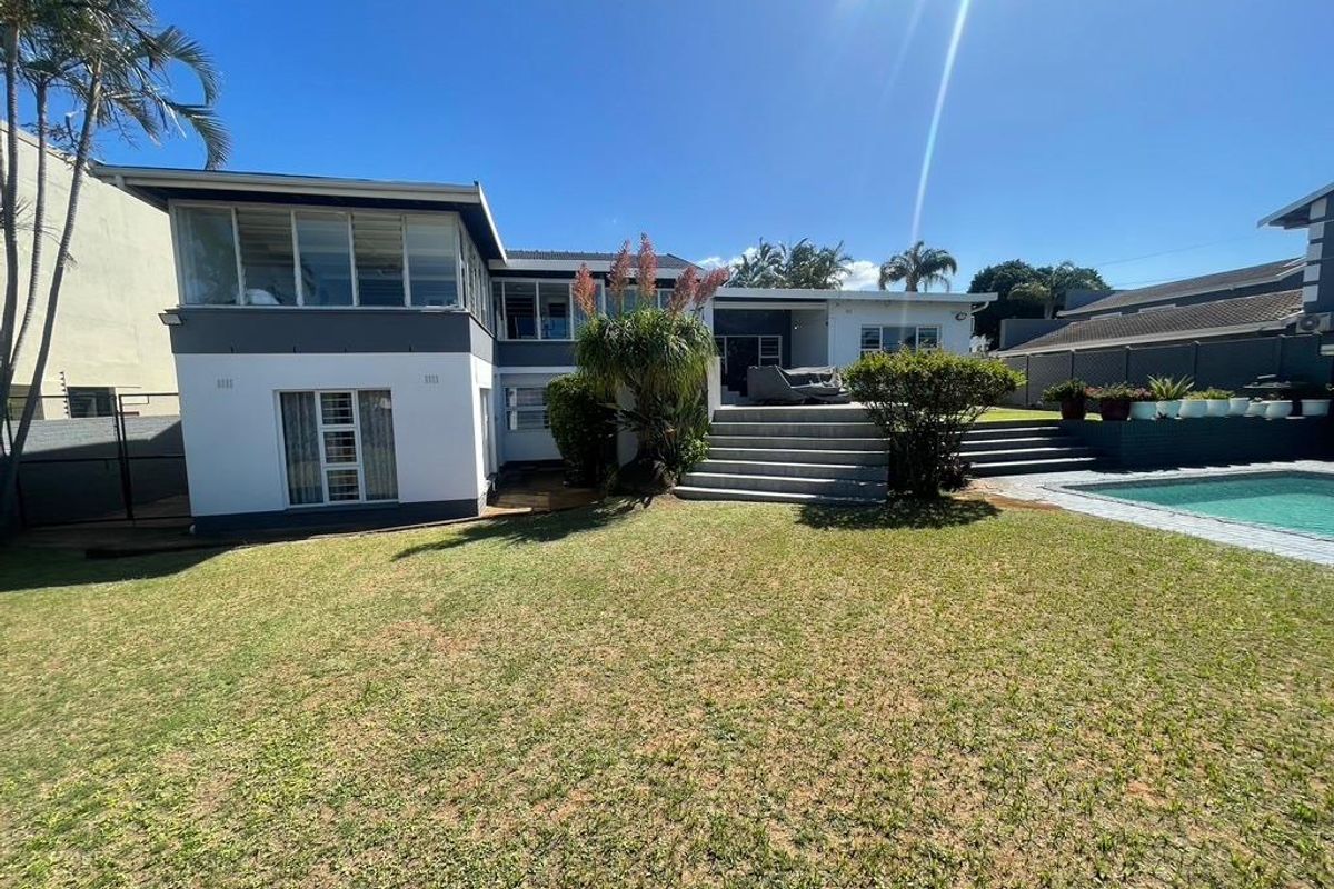 Rear view of the property featuring a multi-level exterior, swimming pool, concrete patio steps, and a spacious landscaped garden area.
