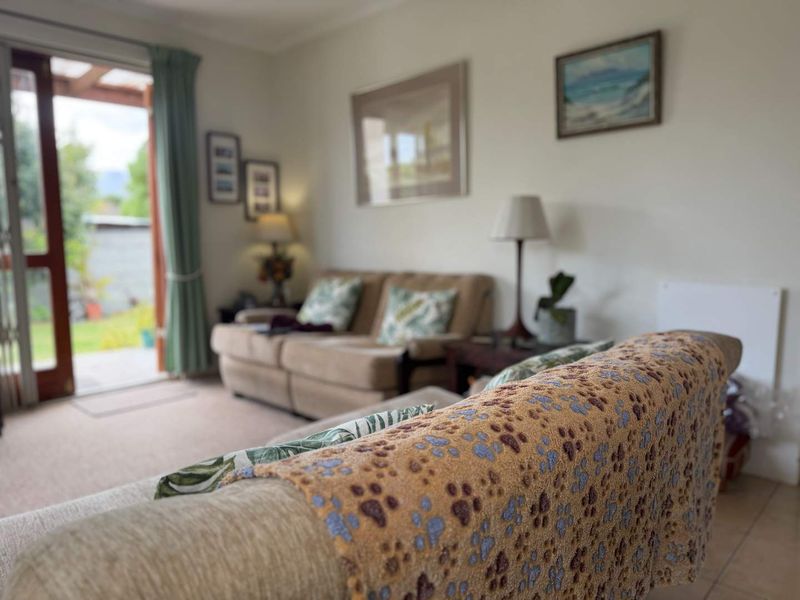 A comfortable living room featuring tiled and carpeted flooring with direct access to an outdoor patio area through a glass sliding door.