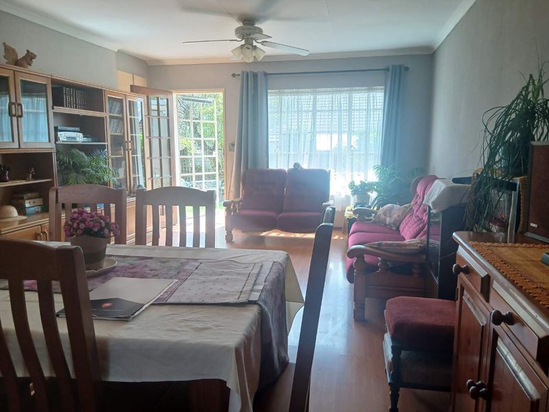 Open plan living and dining area featuring laminate flooring, a ceiling fan, and direct access to the garden through a glass-paneled french door.