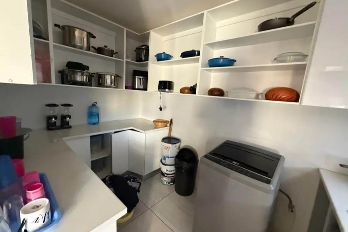 A functional scullery or utility area featuring white built-in cabinetry, open shelving, and tiled flooring, providing ample storage and workspace.