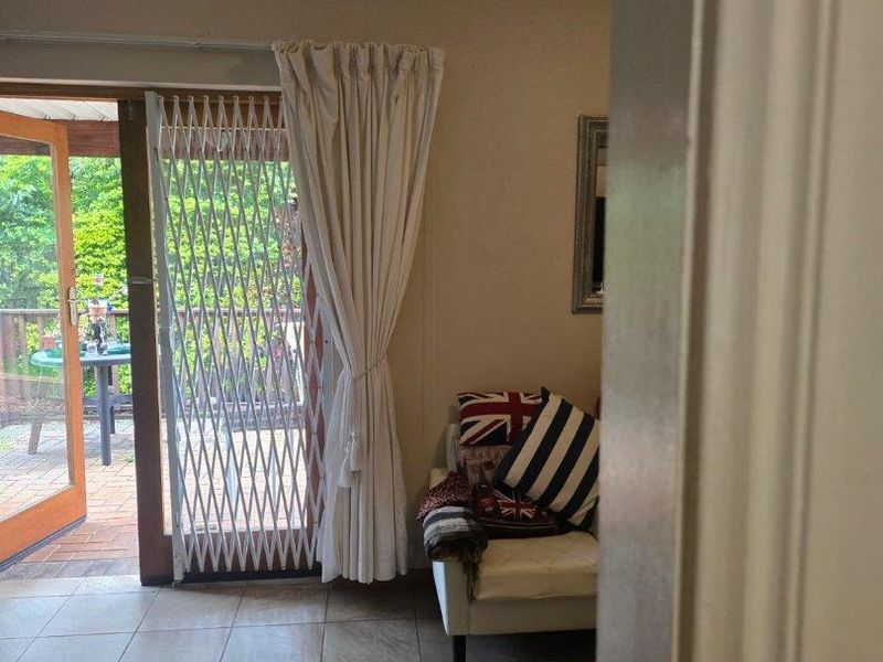 Living room featuring tiled flooring and a sliding glass door with a security gate, providing direct access to an outdoor patio area.