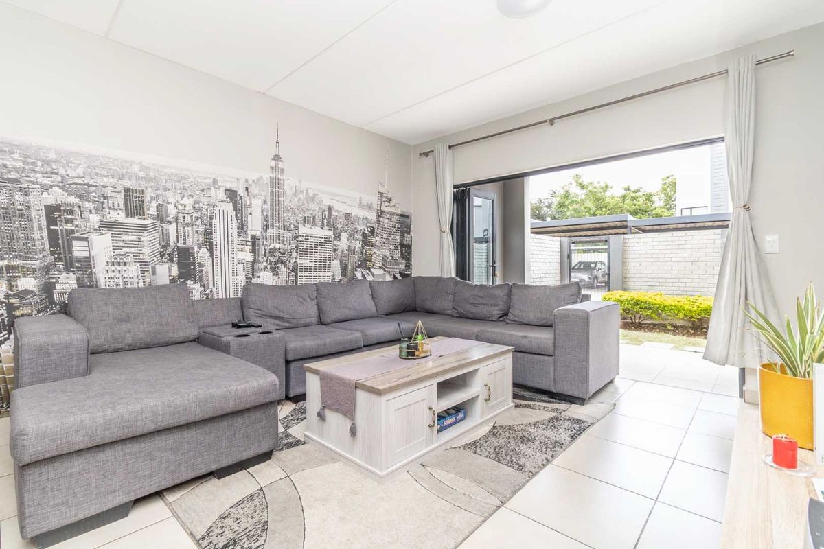 A bright living room featuring large sliding doors that open to an outdoor patio area, finished with neutral floor tiles.