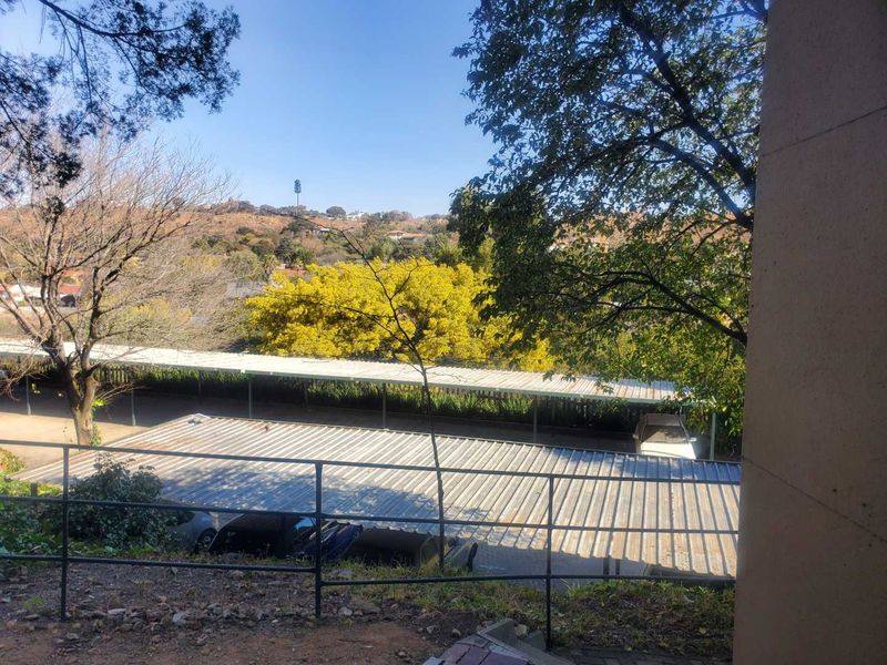 An elevated view overlooking a residential parking area with metal carports and surrounding trees.