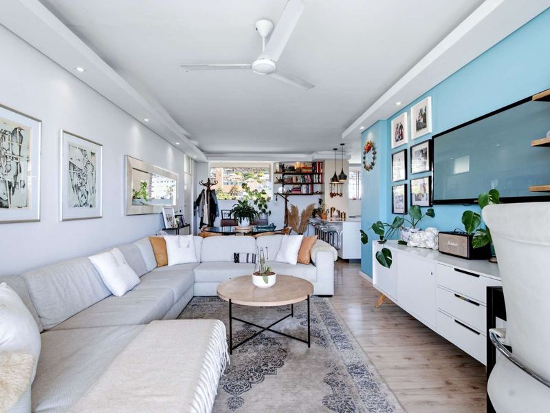 Spacious open-plan living and kitchen area featuring modern laminate flooring, recessed lighting, a ceiling fan, and a functional kitchen island with pendant lighting.