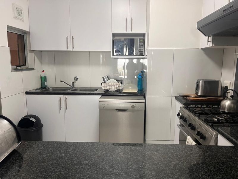 A functional kitchen featuring white cabinetry, granite countertops, a gas stove with extractor, and integrated dishwasher, finished with a clean tiled backsplash.