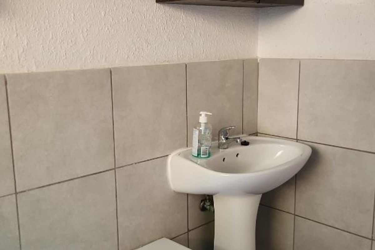 A functional bathroom featuring a pedestal sink, a bathtub with tiled surround, and a wall-mounted mirrored medicine cabinet.