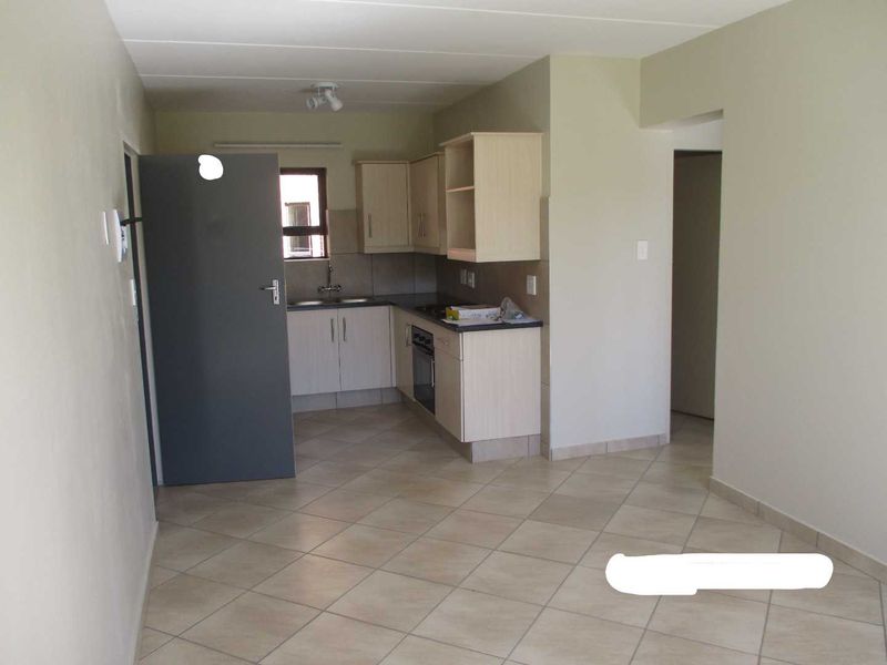 An open-plan living area featuring a functional kitchen with built-in cabinetry, oven, and tiled flooring throughout the space.