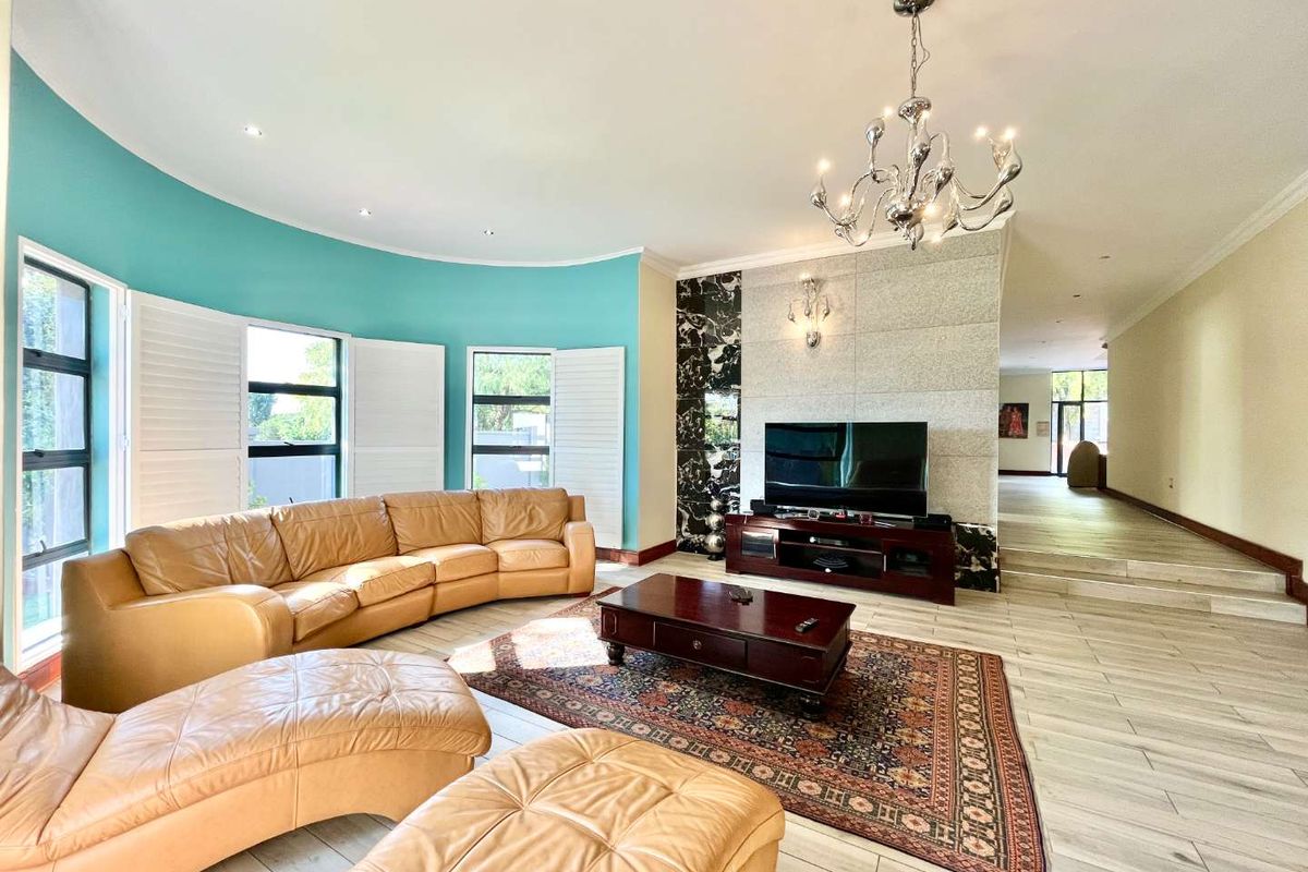 Spacious living room featuring a curved wall, tiled flooring, plantation shutters, and a decorative feature wall with integrated lighting.