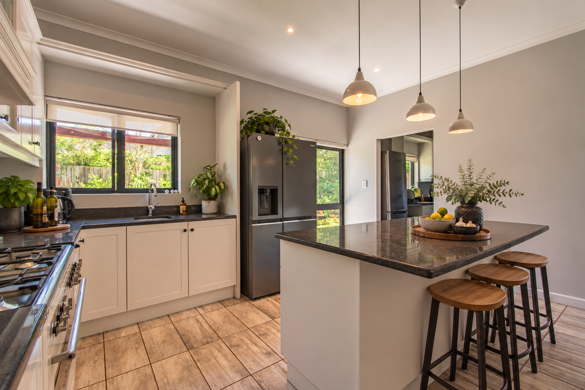 Modern kitchen featuring a central island with granite countertops, shaker-style cabinetry, gas cooktop, and stylish pendant lighting, complemented by durable tiled flooring.