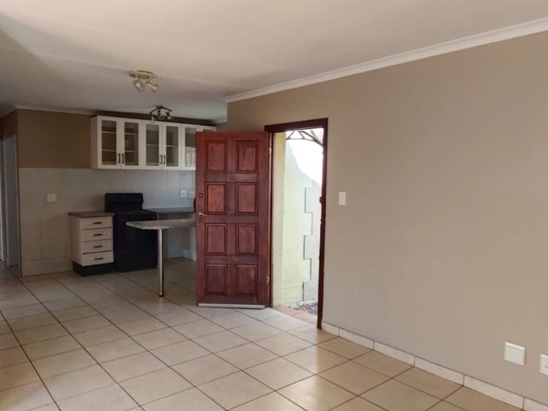 Open-plan living area featuring tiled flooring, a functional kitchen with built-in cabinetry, a breakfast counter, and direct access to the exterior.