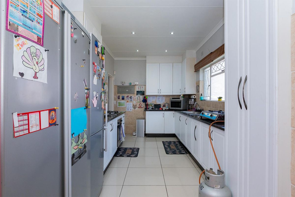 A functional kitchen featuring white cabinetry, tiled flooring, recessed lighting, and a gas hob, offering a practical layout for daily meal preparation.