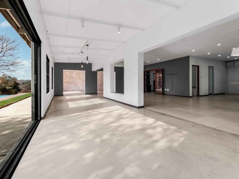 Spacious open-plan living area featuring large sliding glass doors, neutral tiled flooring, and modern recessed lighting, seamlessly connecting to the kitchen and outdoor space.