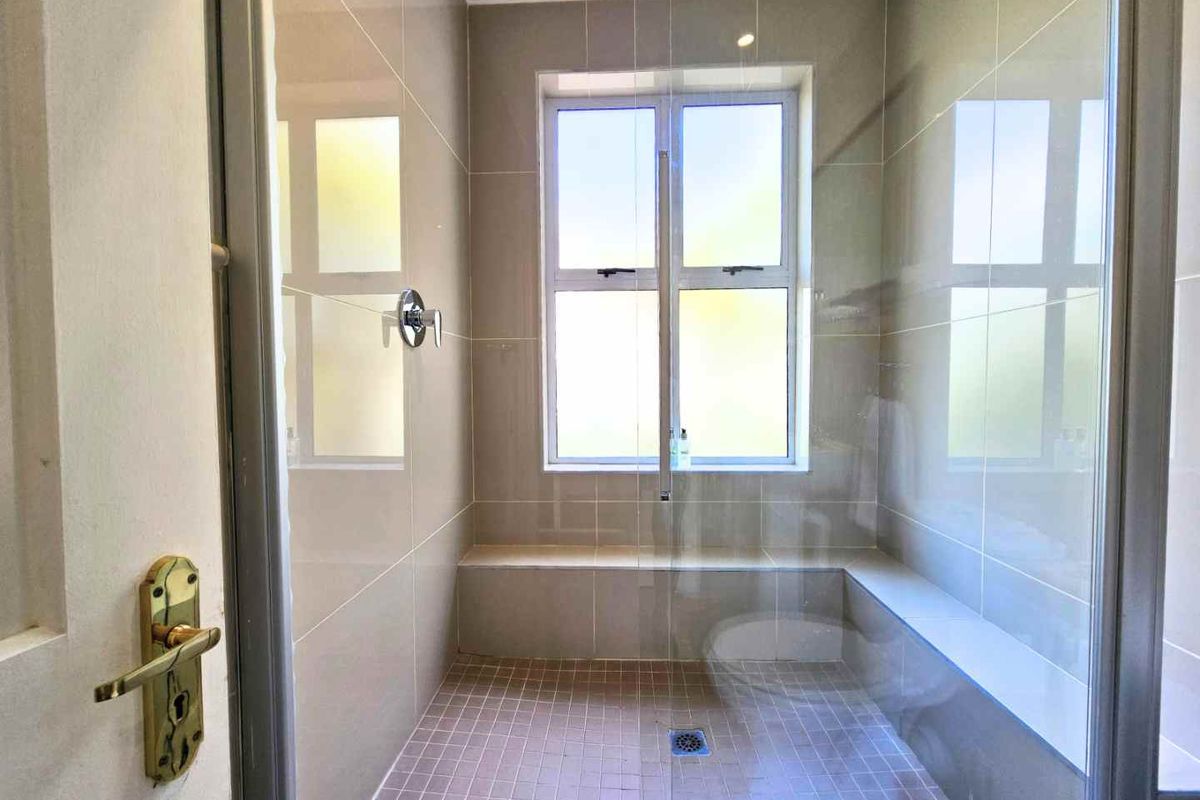 A clean, modern walk-in shower featuring neutral wall tiles, a built-in bench, and a glass enclosure.