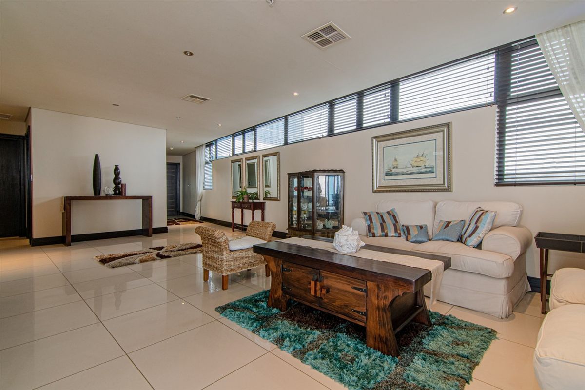 Spacious open-plan living area featuring large format floor tiles, recessed downlighting, and a long row of clerestory windows providing ample natural light.