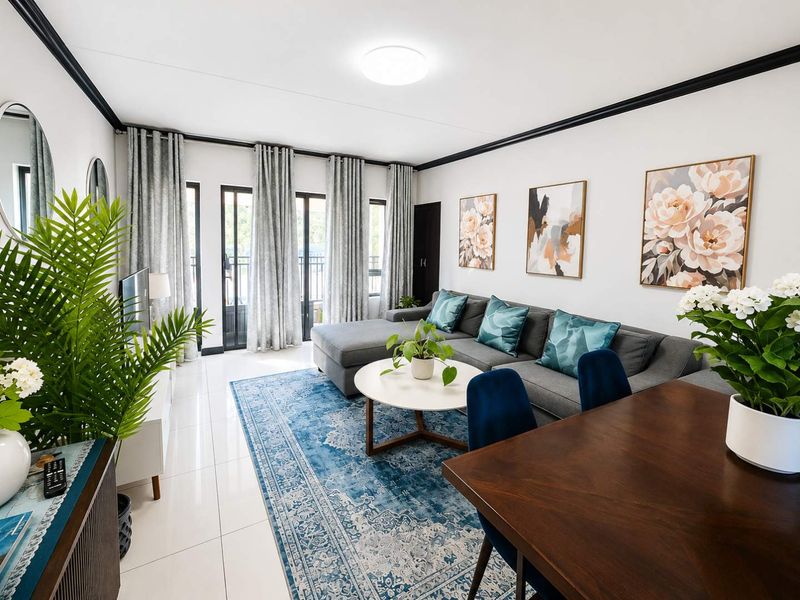 A bright and well-maintained living room featuring tiled flooring, crown molding, and large sliding glass doors that provide access to an outdoor area.