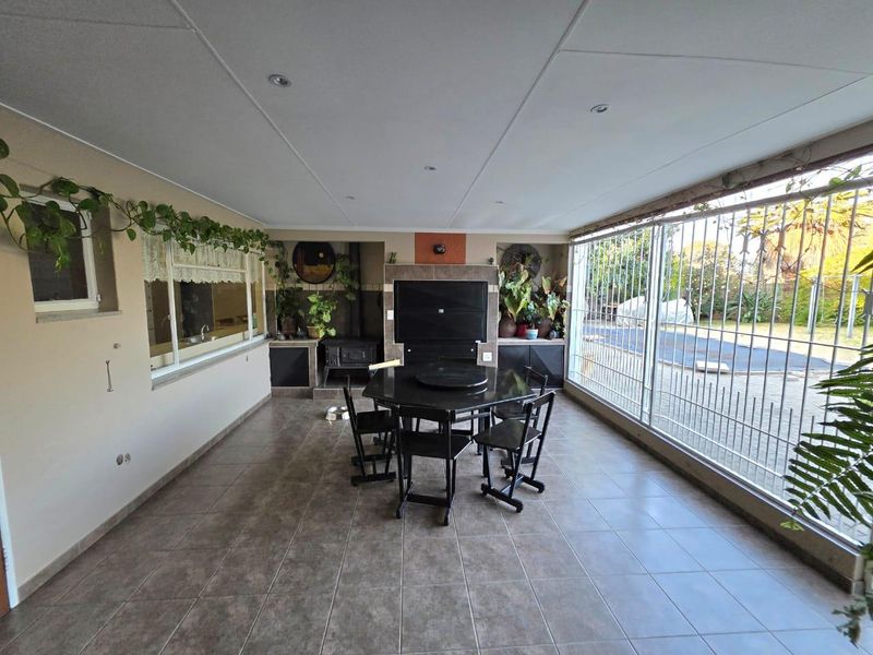 Enclosed patio area featuring a built-in braai, wood-burning stove, and tiled flooring, offering a versatile space for indoor-outdoor entertaining.